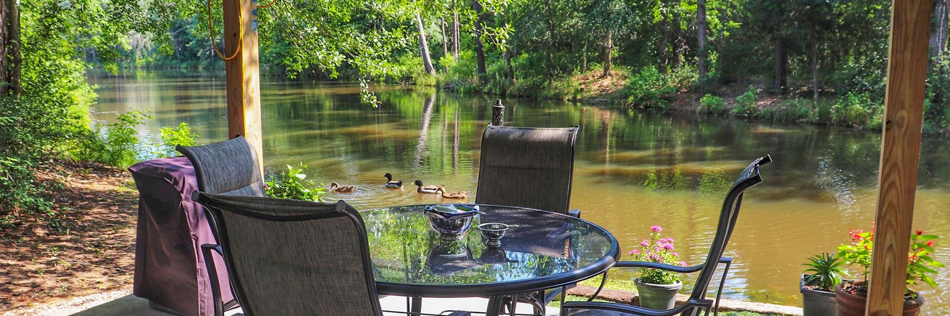 shaded chairs and table next to water and trees