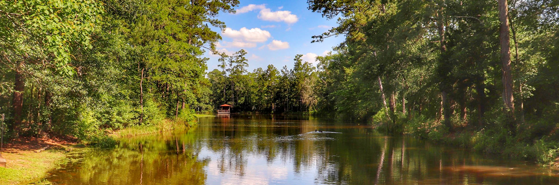 landscape with large body of water, pergola, trees, and clouds